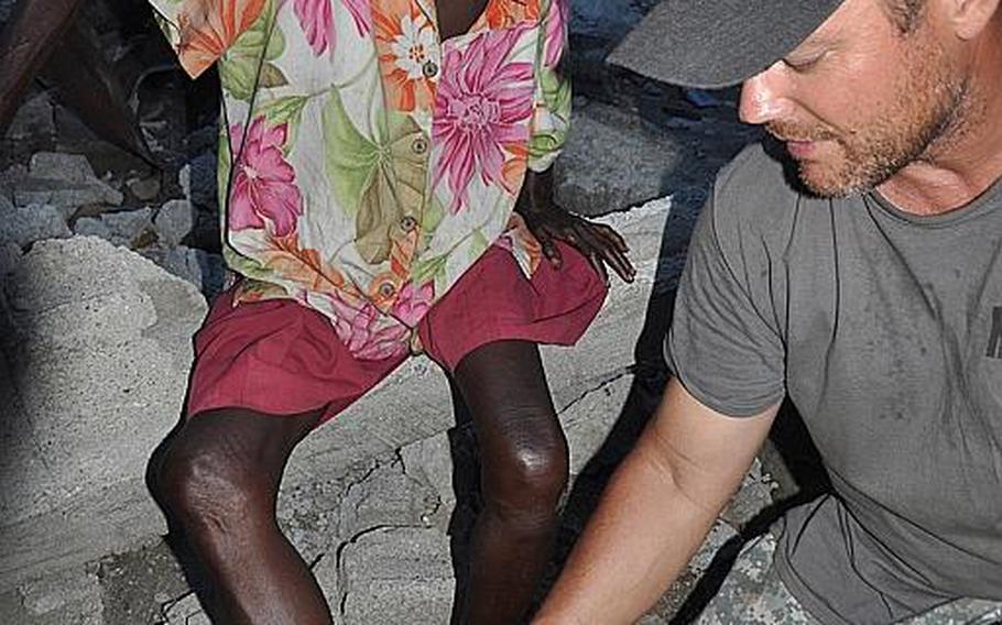 Navy veteran Burke Bryant, right, founder of Humanitarian Aid and Rescue Project, changes the bandage on a woman in the village of Jabouin in southwestern Haiti on Oct. 17. Burke and fellow volunteers have been providing basic medical help and arranged for the delivery of food and medicine to the village after it took a direct hit from Hurricane Matthew.