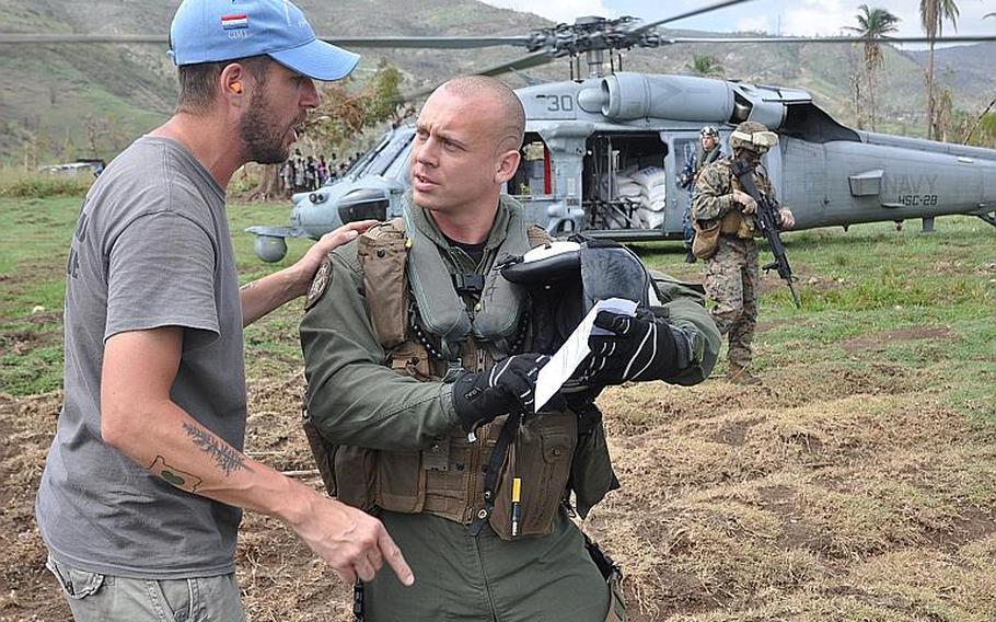 William Gagan, of the Humanitarian Aid and Rescue Project, talks with a Navy helicopter crew member during the delivery of relief supplies to the southwest Haiti village of Jabouin on Oct. 18. Gagan's organization arranged for the aid drop, and is working with other volunteers to provide basic medical help to villagers after Jabouin was struck by Hurricane Matthew.