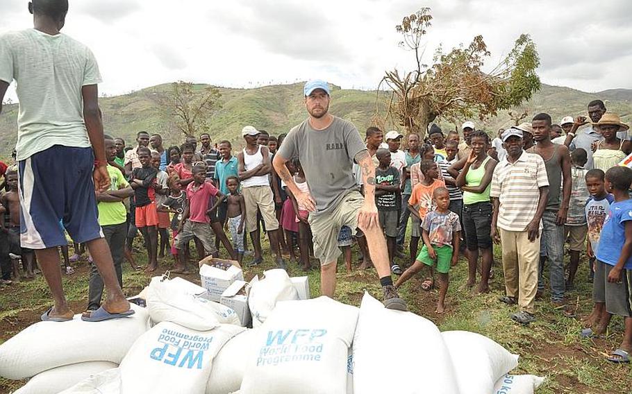 William Gagan, of the Humanitarian Aid and Rescue Project, guards a delivery of relief supplies to the southwest Haiti village of Jabouin on Oct. 18, with the help of one of the villagers. Gagan's organization arranged for the aid drop, and is working with other volunteers to provide basic medical help to villagers after Jabouin was struck by Hurricane Matthew.