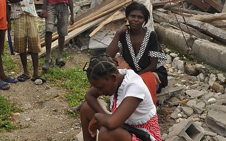 A family sits atop the rubble of their home in the village of Jabouin in southwestern Haiti on Oct. 18, after taking a direct hit from Hurricane Matthew two weeks ago. The woman uses the megaphone to walk around the village in the morning urging her neighbors to put their faith in Jesus.
