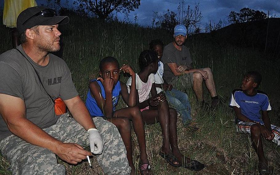 Burke Bryant, left, and William Gagan, far right, of the Humanitarian Aid and Rescue Project, take a few moments rest with the children in the southwest Haiti village of Jabouin on Oct. 17.