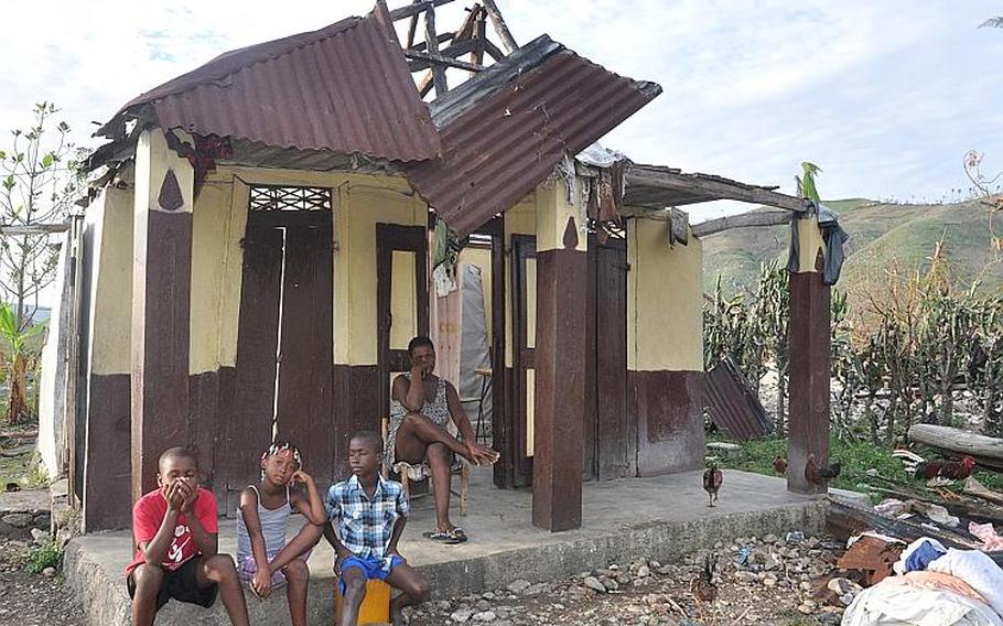 Joseph Rose Yvette and her three children sits on the porch of their roofless home on Oct. 18, after Hurricane Matthew took not only the shelter for the five-member family, but also the crops she sells at market to make a living.