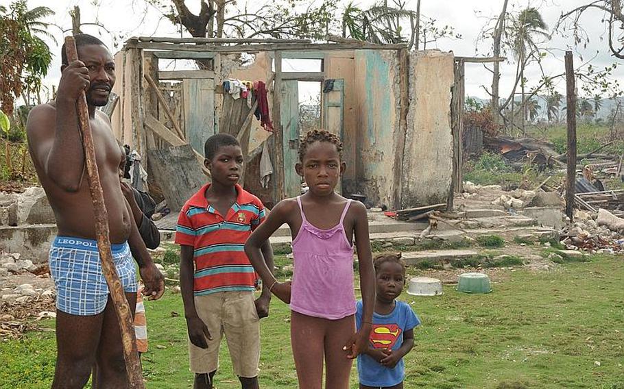 A family stands outside a destroyed home in southwest Haiti on Oct. 18, along the road between the southern coastal city of Les Cayes and the village of Jabouin in the nearby mountains. Hurricane Matthew smacked into the region two weeks ago, leaving an estimated 90 percent of the homes damaged or destroyed. damaged or destroyed.