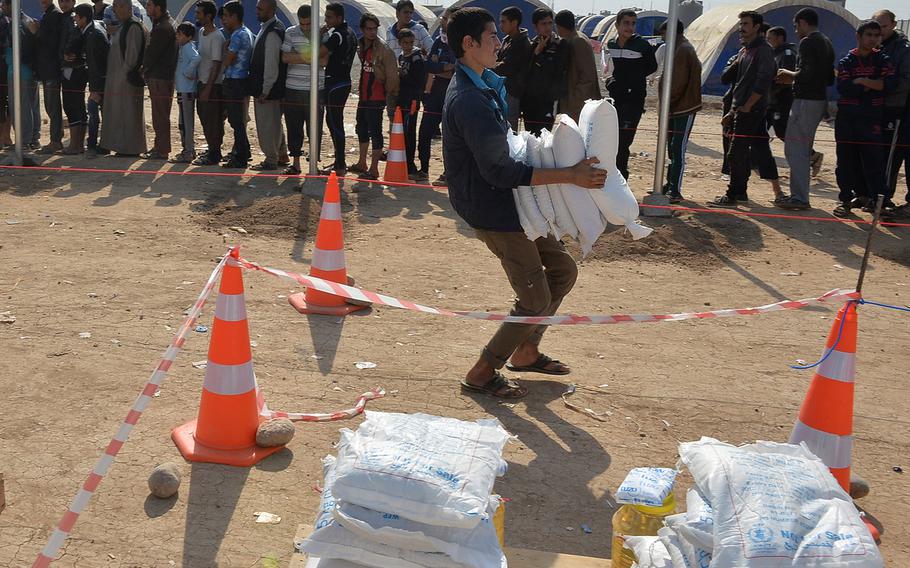 A young man carries away a monthly family food ration at the Khazir displacement camp in Hassan Sham, about 20 miles east of Mosul, Iraq, on Monday, Nov. 7, 2016. Chad Garland/Stars and Stripes