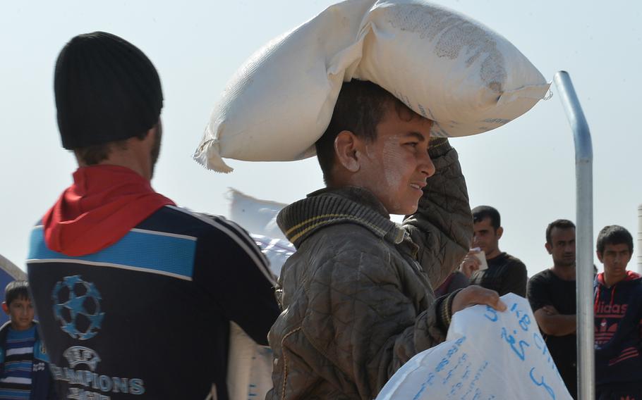 A young boy carries away a portion of a monthly family food ration from the World Food Program at the Khazir displacement camp near Mosul, Iraq, on Monday, Nov. 7, 2016. The ration includes more than 70 kilograms (about 150 pounds) of dry foods, such as rice, flour, beans, chick peas, sugar and salt, and cooking oil.