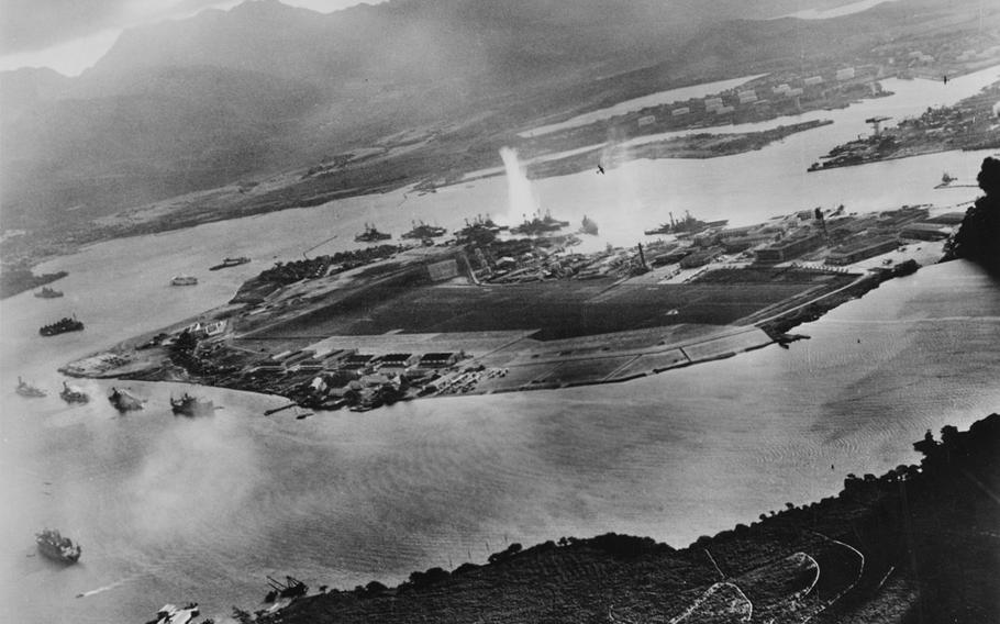 A photo taken from a Japanese aircraft Dec. 7, 1941, shows the beginning of the attack on Battleship Row in Pearl Harbor, during which the USS Oklahoma takes a direct hit on the far side of Ford Island. The USS Arizona is two rows to the left and paired with a smaller vessel.