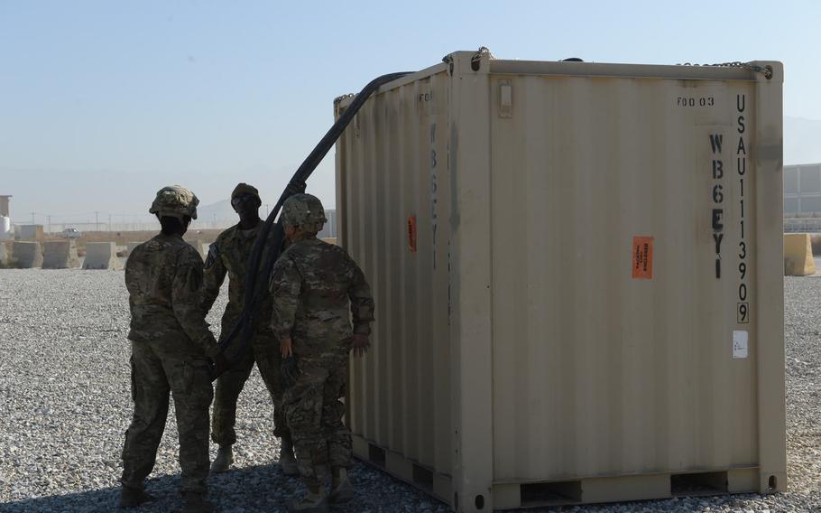 Three U.S. servicemembers attach a cable to a nearly 5,000-pound piece of cargo at Bagram Air Field on Dec. 5, 2016. The loaders attach cargo to helicopters for shipment to smaller bases in central and eastern Afghanistan.
