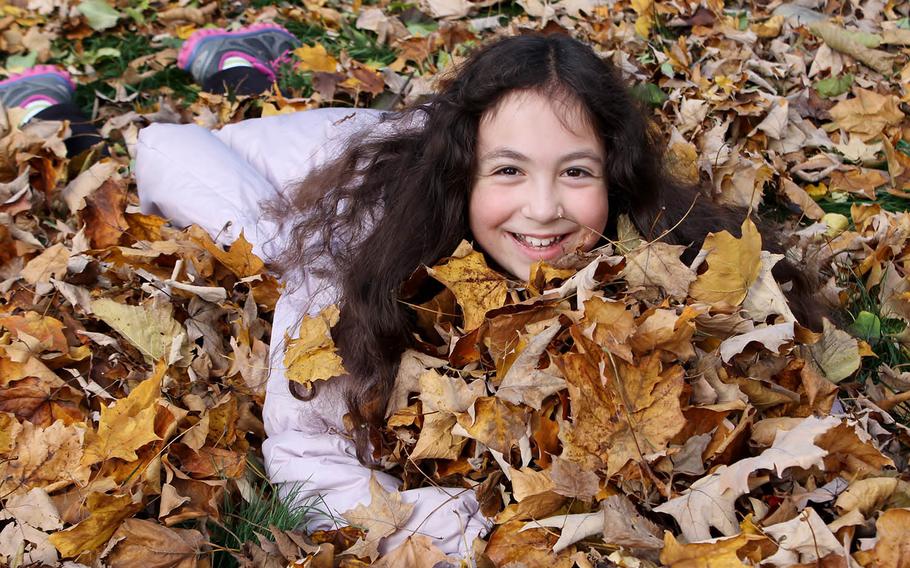 Eliana Adler take a minute to play in the leaves.