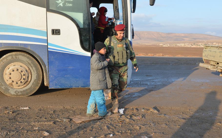A Kurdish soldier talks to a boy, one of about 450 fleeing civilians who arrived on buses at this medical aid station near Mosul, on Saturday, Dec. 17, 2016. Aid workers gave the civilians food, water and clothing, and offered them medical aid.