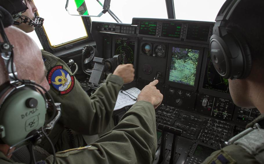 Col. Kenneth Moss, center, 374th Airlift Wing commander, checks a map on a C-130J Super Hercules display during a training flight over Tokyo Bay in July.