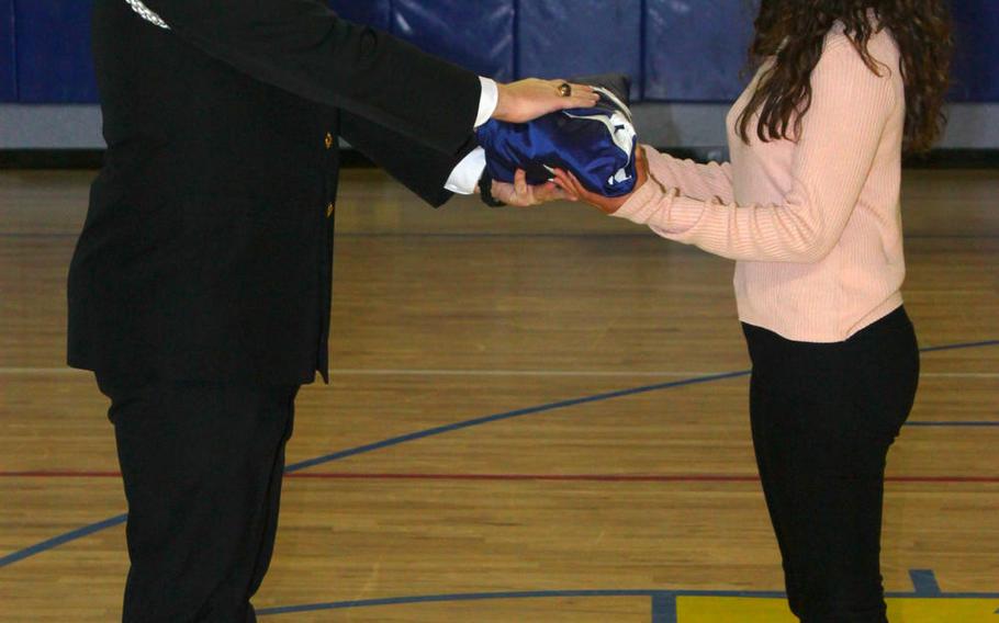 Amaya Wasai, an eighth-grader at Sigonella Middle/High School in Sicily, Italy, receives a folded U.S. flag during a ceremony Tuesday, Jan. 10, 2017, at the school. Amaya is one of 20 students from Sigonella traveling to Washington to participate in the presidential inaugural parade on Jan. 20.