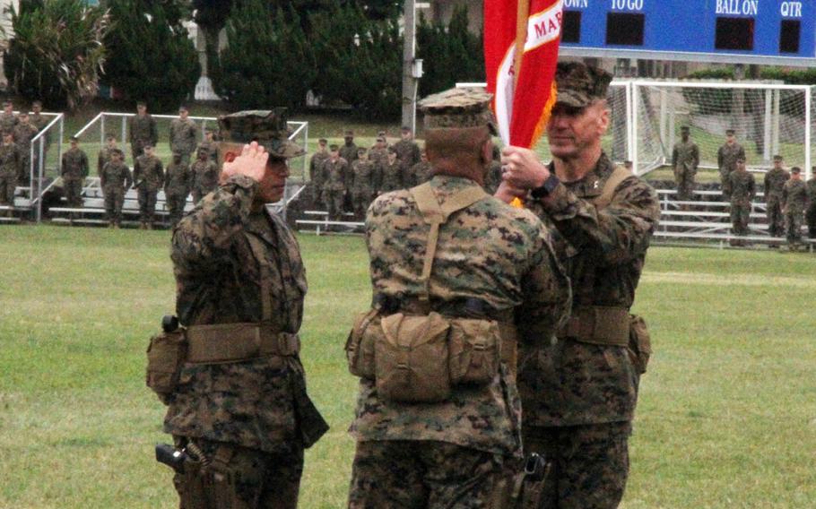 Maj. Gen. Richard Simcock II, right, the outgoing 3rd Marine Division commander, passes the division banner to Maj. Gen. Craig Timberlake during a change-of-command ceremony at Camp Courtney, Okinawa, Friday, Jan. 20, 2017. Sgt. Maj. Vincent Santiago, left, the division's top enlisted leader, salutes.