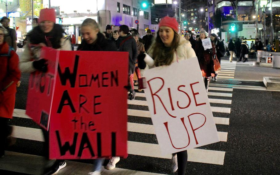 Marchers hold signs as they cross the street in central Tokyo on Jan. 20, 2017.