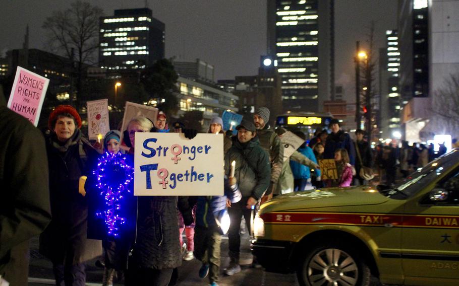 A taxi cab yields to the Women's March in central Tokyo on Jan. 20, 2017. There was a heavy police presence directing traffic and marchers during the event.