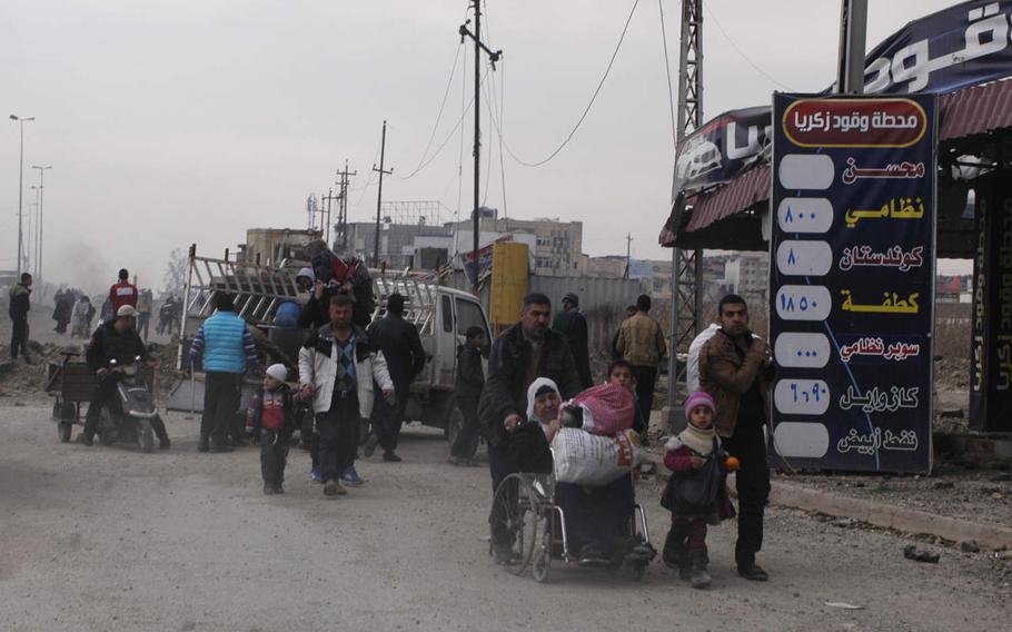 Mosul residents walk through a recently liberated neighborhood on Saturday, Jan. 21, 2017. 