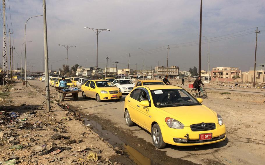 Cars and bicycles pass along a road near Mosul University on Saturday, Jan. 21, 2017. 