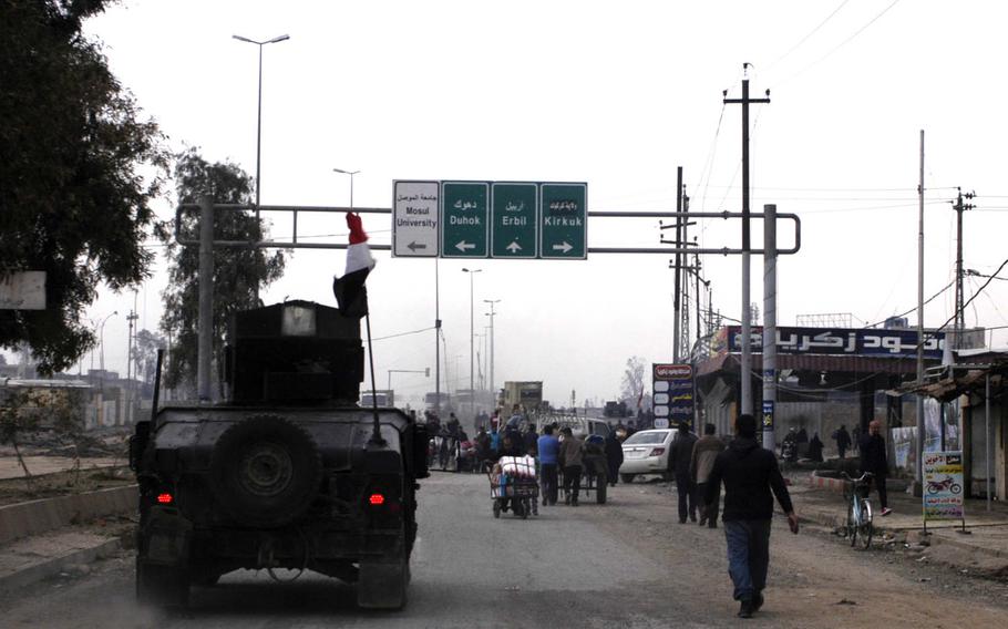 An Iraqi special forces Humvee passes pedestrians in Mosul on Saturday, Jan. 21, 2017.