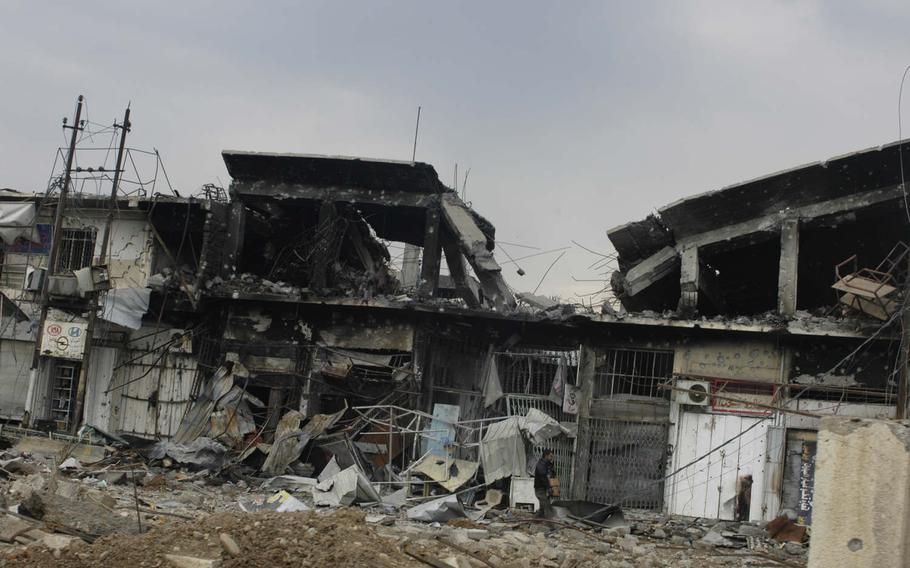 A man clears up damage from fighting in Mosul, Iraq, on Saturday, Jan. 21, 2017. 