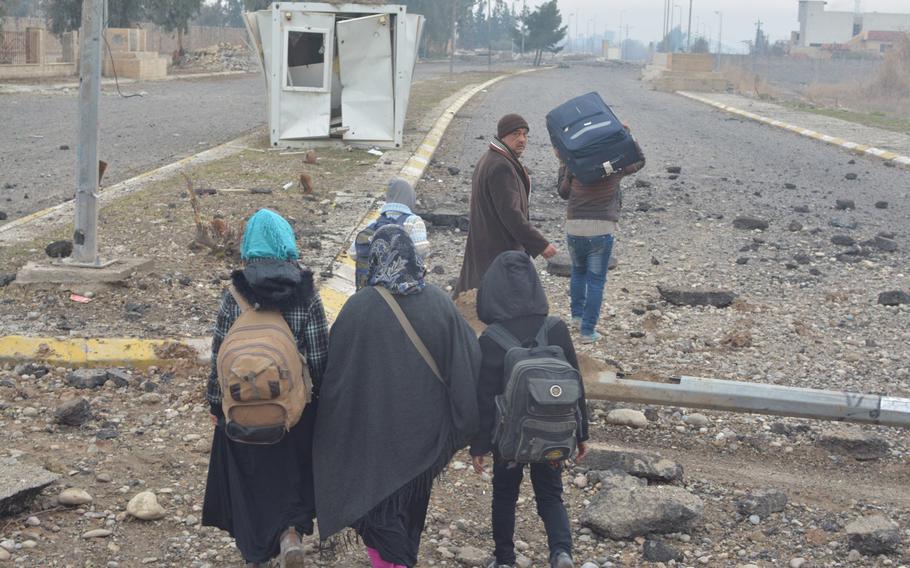 Residents clamber over debris on their way back to Mosul's Hay al-Arabi neighborhood Wednesday, Jan. 25, 2016.
