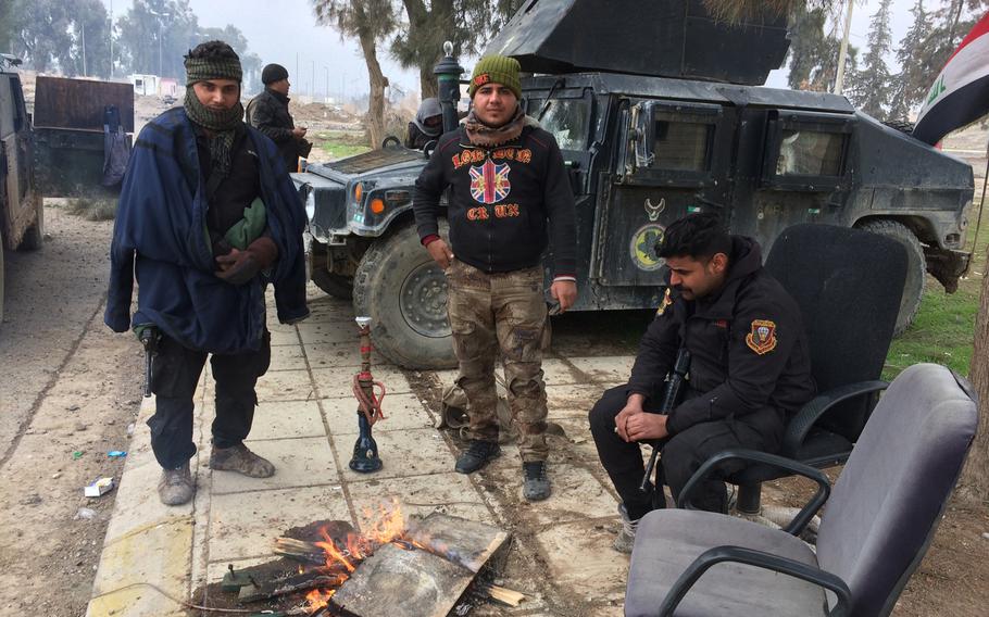 Iraqi troops stay warm in front of a palace in Mosul, Iraq, on Wednesday, Jan. 25, 2017.