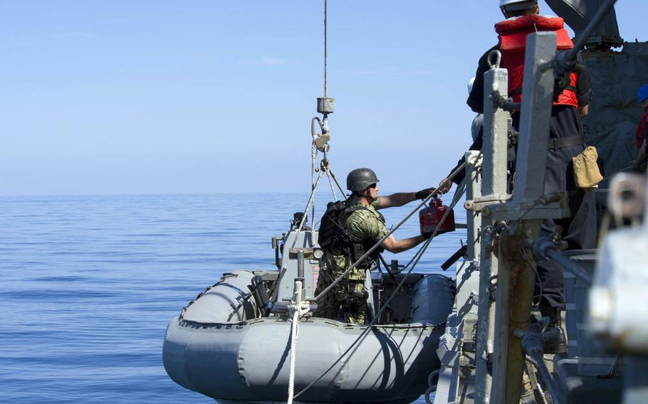 Boatswain's Mate 1st Class Alan Farthing, assigned to the guided-missile destroyer USS Cole, places a container of fuel into a rigid-hull inflatable boat after a distress call from an Iranian-flagged dhow in the Gulf of Oman, Friday, Jan. 27, 2017.