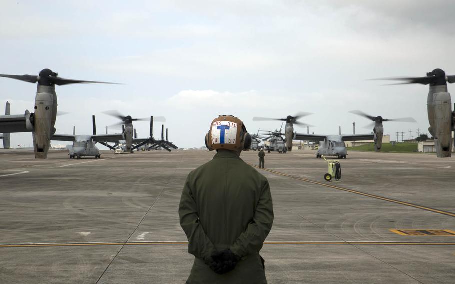 A Marine waits to guide MV-22 Ospreys with Marine Medium Tiltrotor Squadron 265, 31st Marine Expeditionary Unit, during their takeoff from Marine Corps Air Station Futenma, Okinawa.