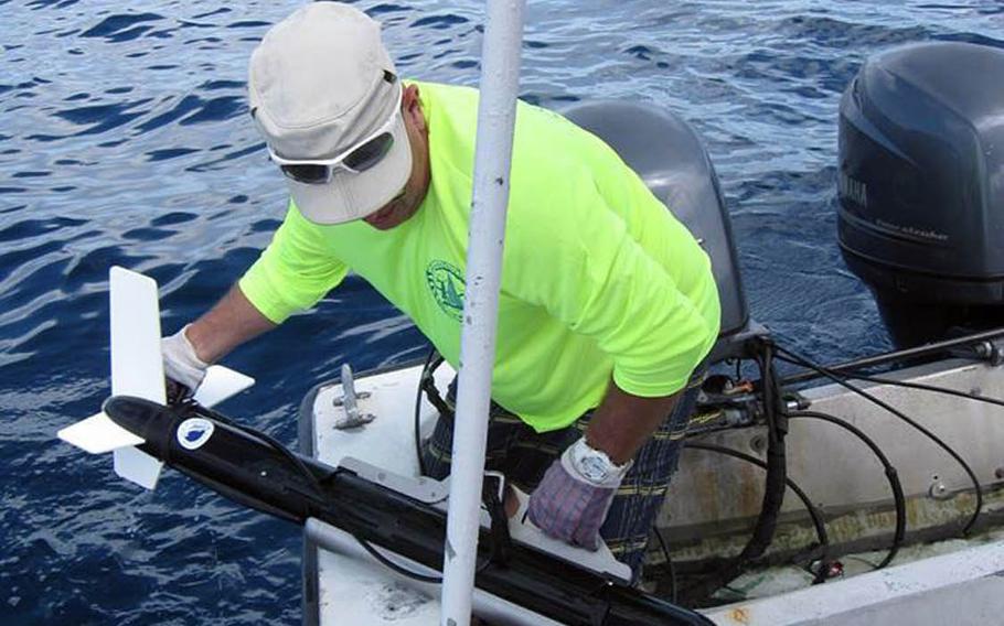 Tim Roberge of the Kwajalein MIA Project lifts a sonar into his boat after a search for missing World War II aircraft in the waters of the Kwajalein Lagoon, Marshall Islands.