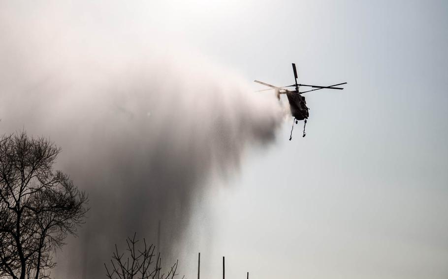 A helicopter drops water onto a grass fire that spread to Osan Air Base, South Korea, Monday, April 3, 2017.