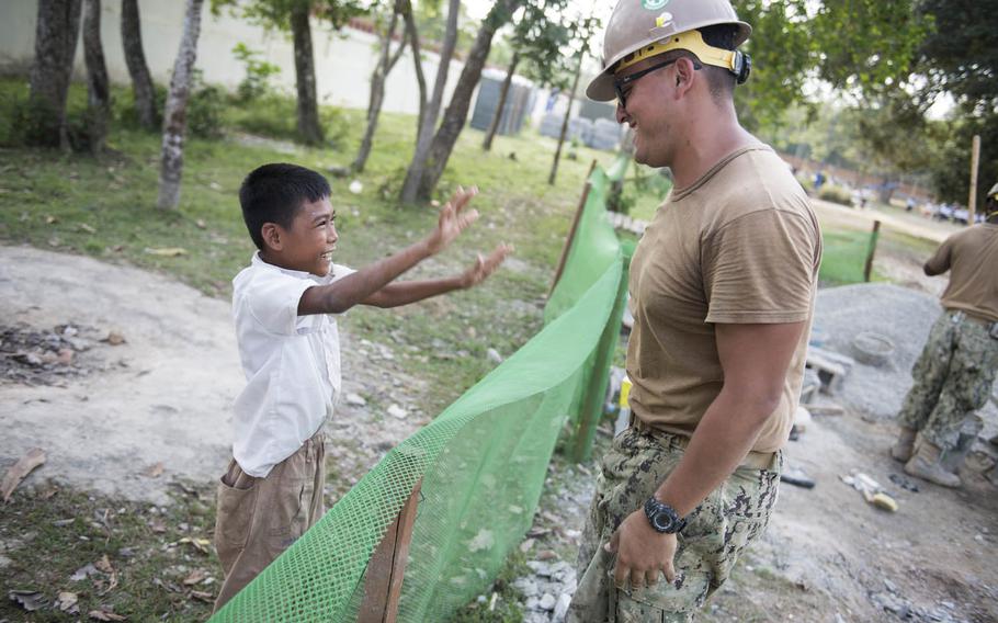 Builder 2nd Class Jaime Buitrago, assigned to Naval Mobile Construction Battalion 5, greets a Cambodian student during a break from helping build a five-stall bathroom at a school in Svay Rieng Province, Cambodia, in January.