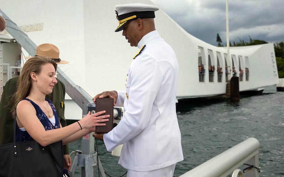 Jessica Marino, granddaughter of USS Arizona survivor Raymond Haerry, bids farewell as Rear Adm. John Fuller of Navy Region Hawaii prepares to deliver Haerry's cremated remains to Navy and Park Service divers for interment inside the hull of the USS Arizona in Pearl Harbor, Hawaii, April 15, 2017.