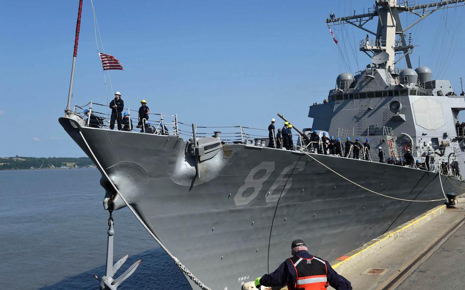 A crewmember of the USS Shoup raises the ship's first Navy jack as it prepares to moor at the Port of Anchorage, Alaska, June 24, 2015, as one of three Navy destroyers participating in Exercise Northern Edge out of the Gulf of Alaska.