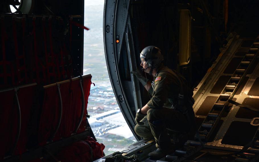Senior Airman Tony Schoof, 25, of Yale, Mich, looks down at Yokota Air Base, Japan, from a C-130H Hercules aircraft, Thursday, April 20, 2017.