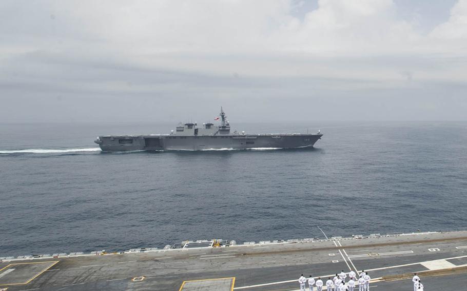 The JS Izumo, a Japanese Maritime Self-Defense Force helicopter destroyer, passes the USS George Washington near Japan in 2015.