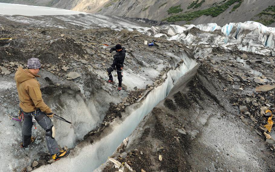 Searchers on Alaska's Colony Glacier anchor themselves to the glacier wall before attempting to search for possible evidence of the 1952 Air Force C-124 crash in a crevasse, June 30, 2013.