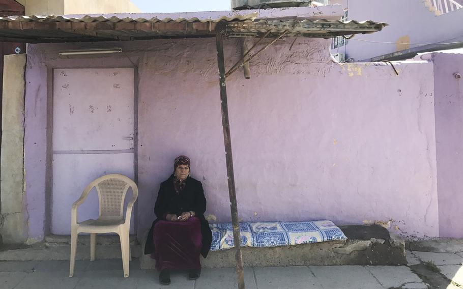 Rakhima Slewa sits out front of her home in Teleskof, Iraq, on March 24, 2017. Slewa fled the village when Islamic State militants advanced but returned in March with her son and daughter-in-law to begin rebuilding a life in her home village.