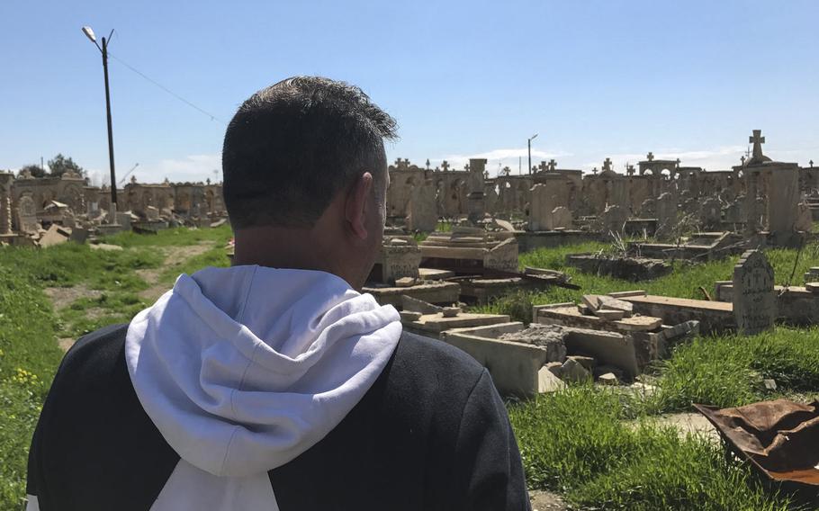 Manhel Mat Yousef walks through a cemetery in the Iraqi village of Teleskof on March 24, 2017. Islamic State militants vandalized the burial ground, where Yousef's mother, father and brother are buried. His home across the street from the cemetery was destroyed in a car bomb blast, and Yousef says he has nothing keeping him in his home village now.