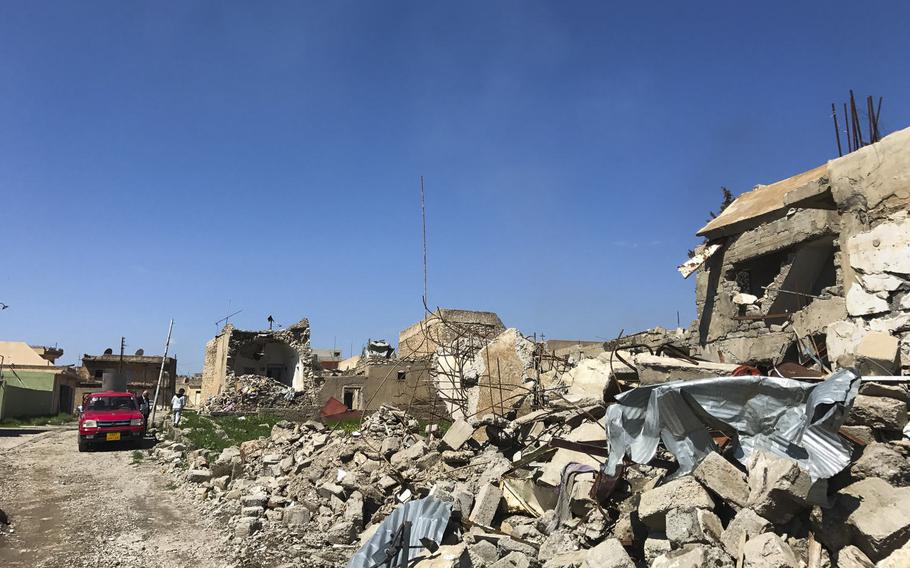 Buildings in the Christian village of Teleskof, Iraq, pictured on March 24, 2017, were turned to rubble in the fighting here. In the background, a man and a young boy inspect damage to a home that's missing an outer wall. Villagers have slowly begun returning to this town, where a U.S. Navy SEAL was killed battling an Islamic State offensive in May 2016.