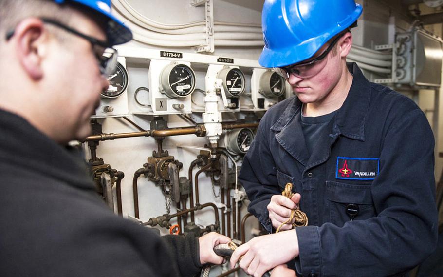 Two damage-control firefighters tie tending line to an electrical submersible pump aboard the aircraft carrier USS George H.W. Bush on March 2, 2016.