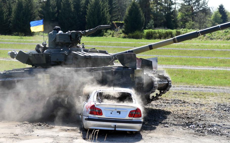 Ukrainian tankers drive a T-64BM tank through a car set up as an obstacle during a portion of the Strong Europe Tank Challenge at Grafenwoehr, Germany, Thursday, May 11, 2017.