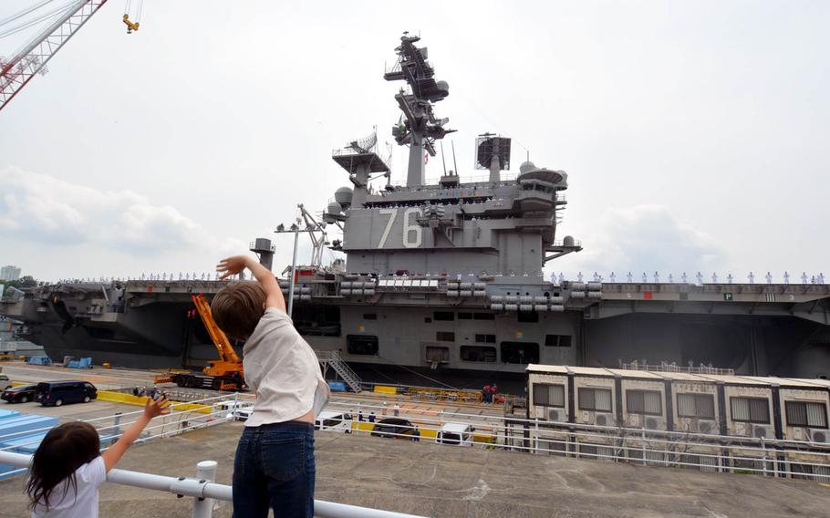 Aryanna Abriam, 10, right, and Ailani Abriam, 4, left, wave goodbye to their father as the aircraft carrier USS Ronald Reagan prepares to depart Yokosuka Naval Base, Japan, Tuesday, May 16, 2017.