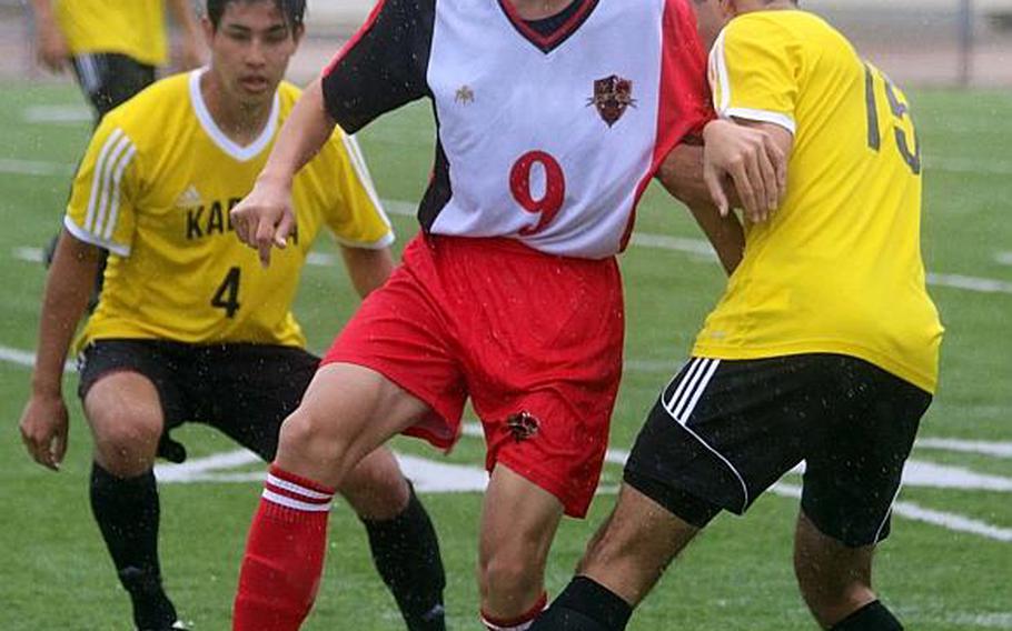 Nile C. Kinnick's Kai Sullivan tries to dribble from between Kadena defenders Seth Garcia and Junta Callahan during Tuesday's round-robin match in the Far East Boys Division I Soccer Tournament, won by Panthers 3-0. KATRICIA AQUINO/SPECIAL TO STRIPES