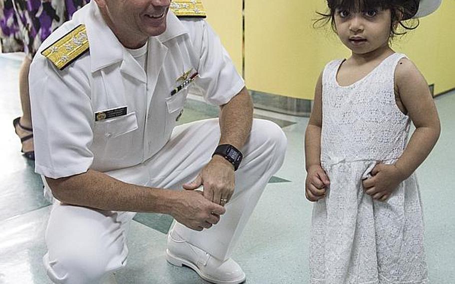 Vice Adm. Kevin M. Donegan, U.S. Naval Forces Central Command commander, meets a young girl as she wears his hat in the children's ward of the American Mission Hospital in Manama, Bahrain on Sunday, May 21, 2017. 
                