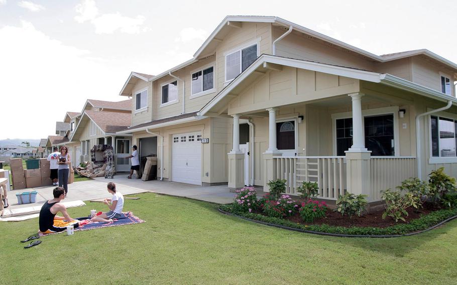Navy family members relax on their front lawn while movers deliver household goods to their new home in 2004.