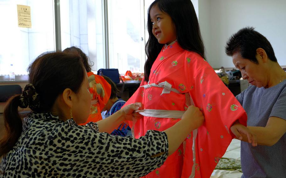 Miya Calata, 6, gives a quick smile as local Japanese volunteers make final touches to her kimono during a charity event in Yokosuka City, Japan, Sunday, June 22, 2017.