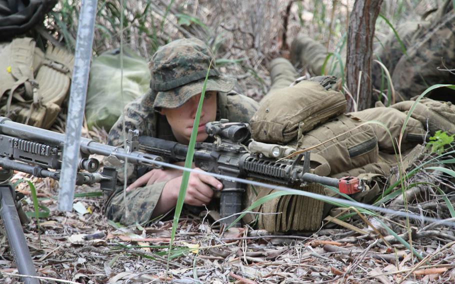A Marine covers the road as troops move inland from Freshwater Beach after a successful joint U.S.-Australian amphibious assault exercise in Queensland, Australia, Wednesday, July 19, 2017. The drill was part of Talisman Saber 2017.