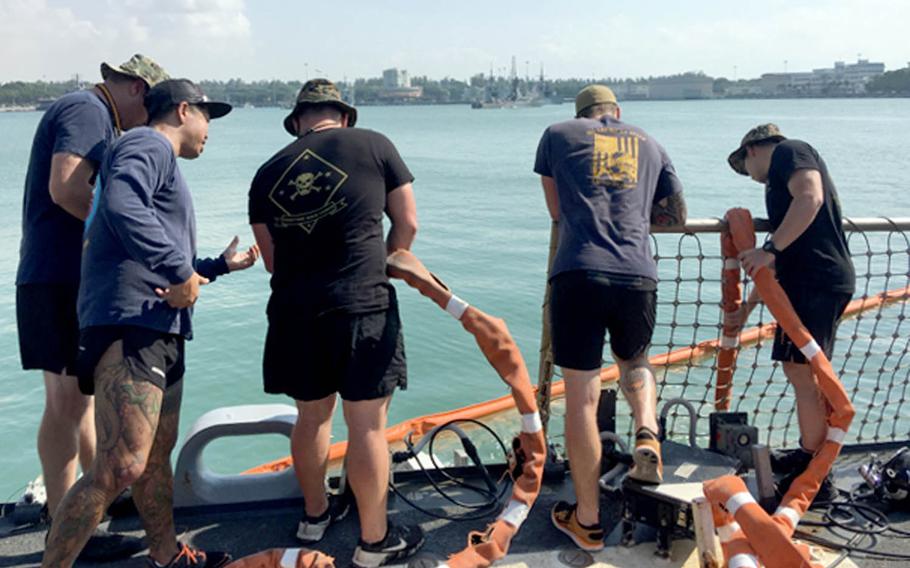 A team of Navy and Marine Corps divers lower a tending line while searching the collision-damaged USS John S. McCain for missing sailors at Changi Naval Base, Singapore, Wednesday, Aug. 23, 2017.