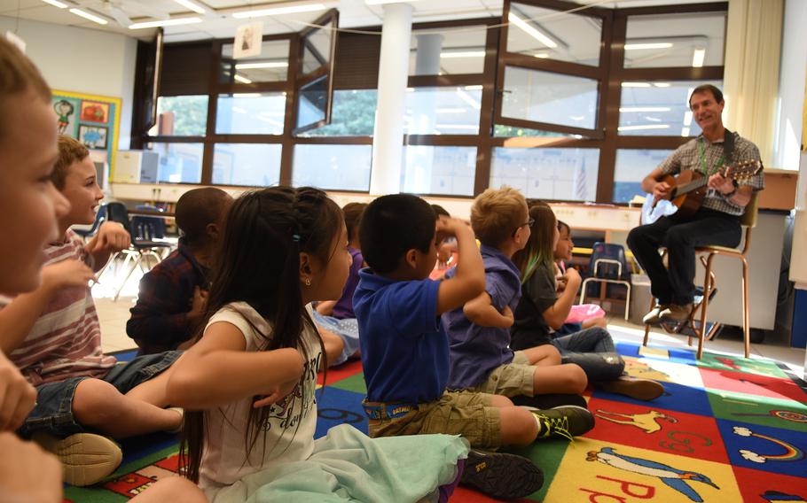 Second-graders at Ramstein Elementary School in Germany laugh and sing along while art teacher Jules Fritz plays some silly songs on the guitar at the end of art class on Monday, Aug. 28, 2017.