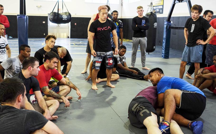 Retired Ultimate Fighting Championship competitor Mark Munoz, in blue shirt, conducts a grappling demonstration during a mixed martial arts clinic at Yokosuka Naval Base, Japan, Saturday, Sept. 2, 2017.