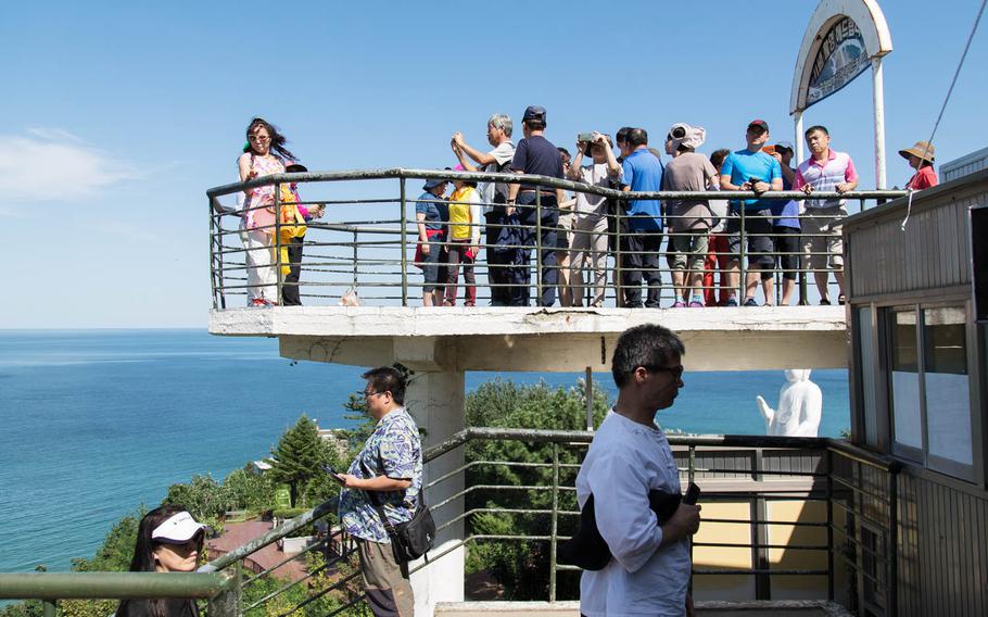 Tourists pose for pictures and walk around a Demilitarized Zone observatory near Goseong, South Korea, Saturday, Aug. 26, 2017.