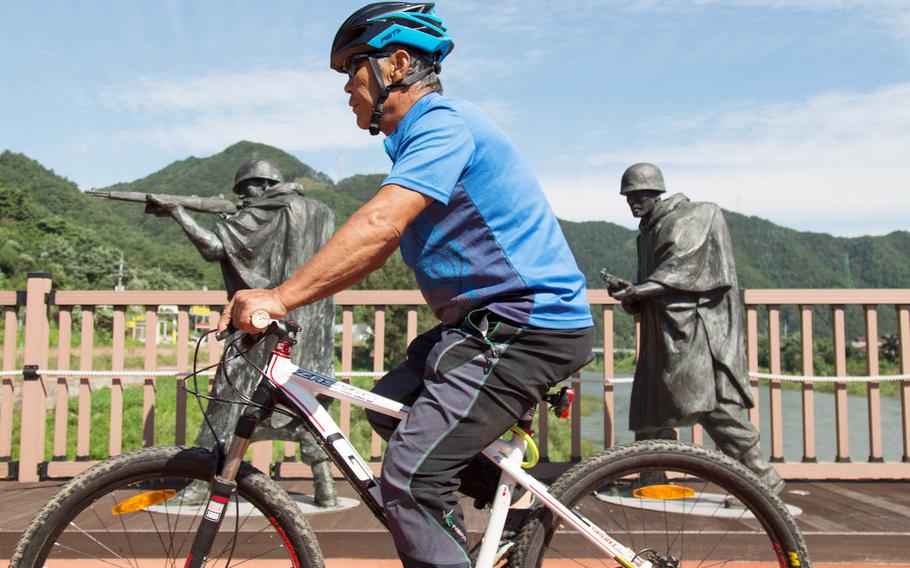 A tourist bikes across a Korean War memorial bridge near Inje, South Korea, Saturday, Aug. 26, 2017.